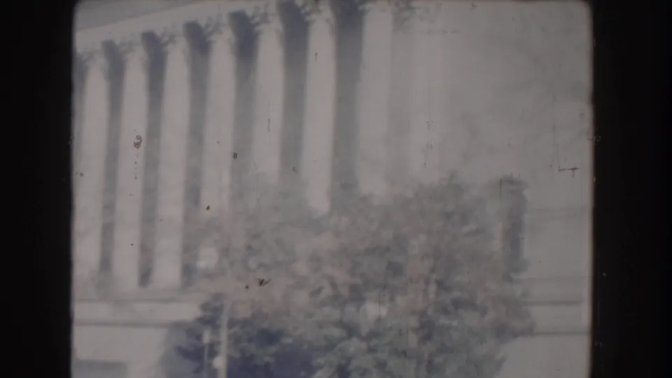 Overexposed 1960 Washington, DC 8mm view with faint classical columns, trees, soft focus, and visible film scratches.