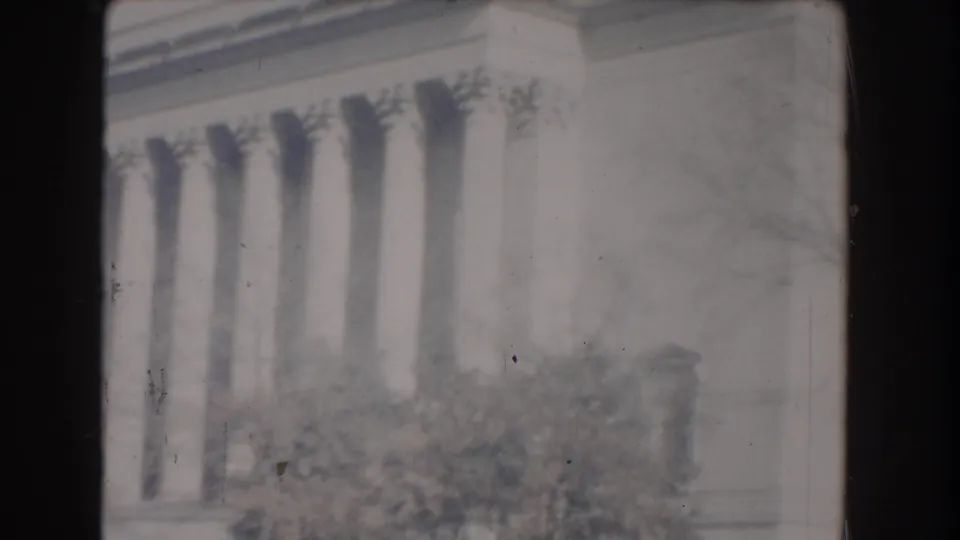 1960 Washington, DC home-movie frame showing pale Jefferson Memorial columns behind shrubs and soft film wear.