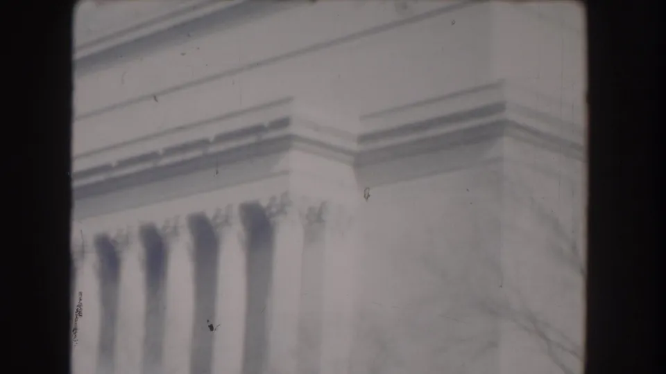 1960 Washington, DC frame with Jefferson Memorial columns, roofline detail, and faint tree branches in soft 8mm color.