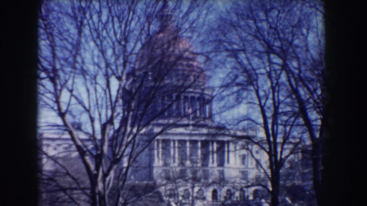 Capitol building behind leafless trees, with dark film edge at the side.