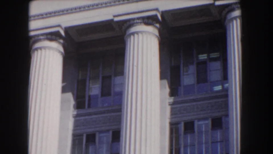 A tilted view shows tall columns, upper windows, and stone trim on a neoclassical building in Washington, DC.