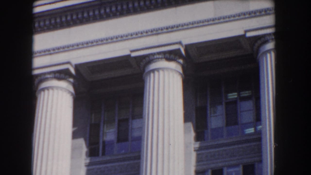 1960 Washington DC 8mm frame showing close architectural details of a white neoclassical building with columns and shadowed windows.