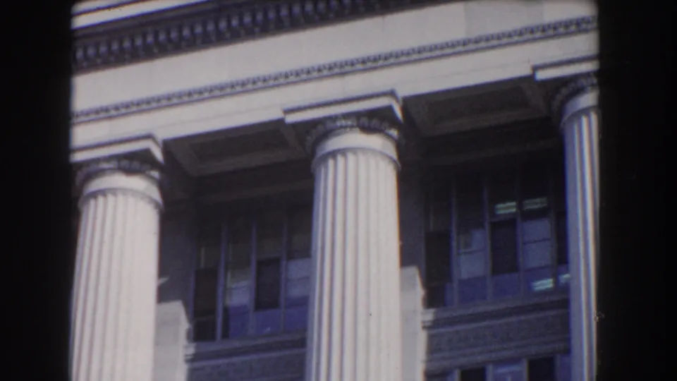 1960 Washington DC 8mm frame showing close architectural details of a white neoclassical building with columns and shadowed windows.