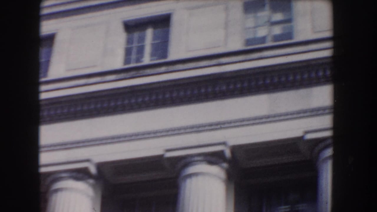 Cropped upper facade with columns, windows, and decorative trim.
