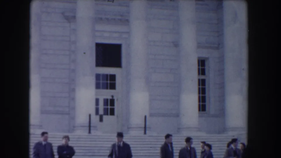 Visitors gather at the base of the memorial steps in a 1960 Washington-area home-movie view with columns and doors behind them.