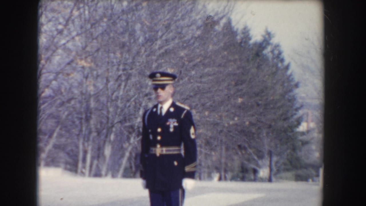 A soldier in a dark ceremonial uniform stands at attention in the winter landscape of the supplied 1960 Washington, DC memorial footage.