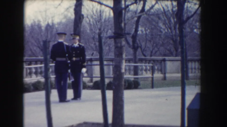 Two uniformed guards face each other near a stone railing and bare trees in the 1960 Washington, DC home-movie clip.