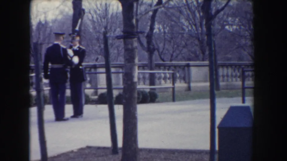 A uniformed soldier holds a rifle upright as another soldier stands nearby during a formal outdoor inspection in 1960 Washington, DC.