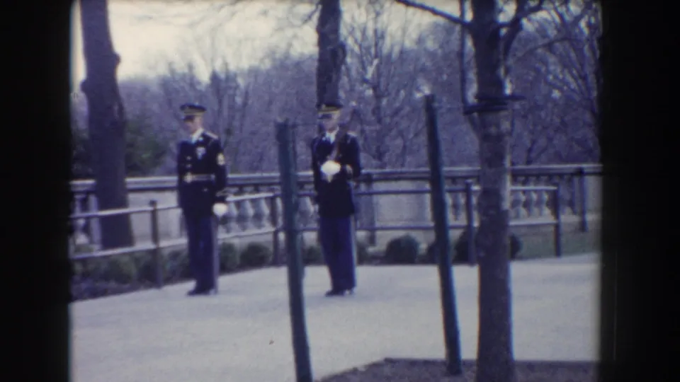 Two military guards remain on the Washington, DC walkway, one with gloved hands raised during a formal movement.