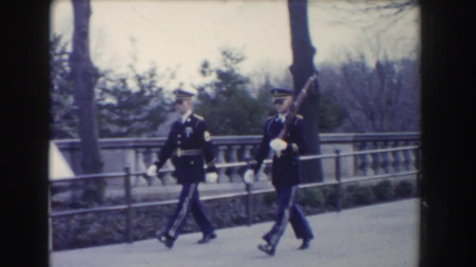 A closer 8mm frame shows two Washington, DC ceremonial guards marching in dark uniforms and white gloves.