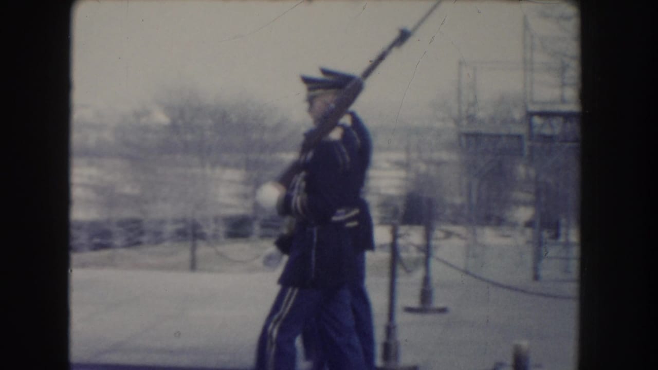 Honor guard marching with a rifle and fixed bayonet near snowy grounds.