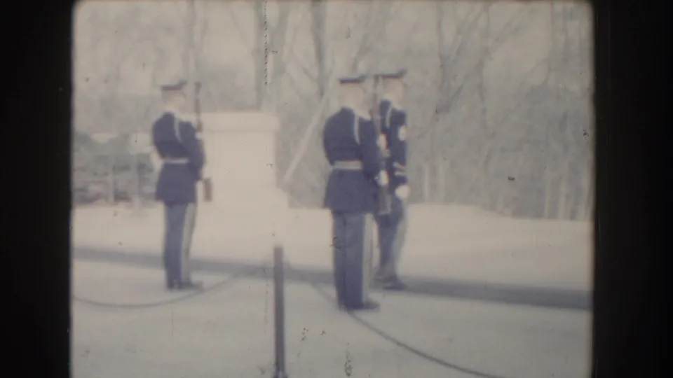 Soft 1960 Washington, DC home-movie frame of guards standing near the Tomb of the Unknown Soldier boundary.