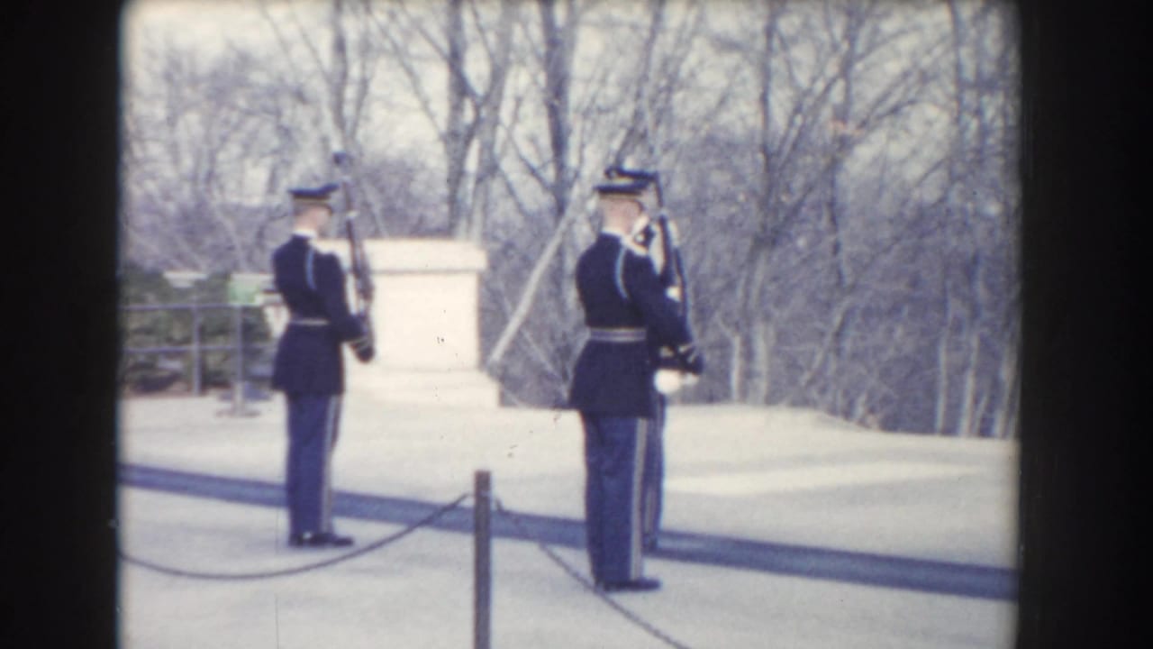 Washington, DC 1960 home-movie frame showing two dark-uniformed guards with rifles standing in a formal outdoor area.