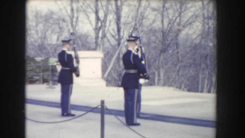 Washington, DC 1960 home-movie frame showing two dark-uniformed guards with rifles standing in a formal outdoor area.