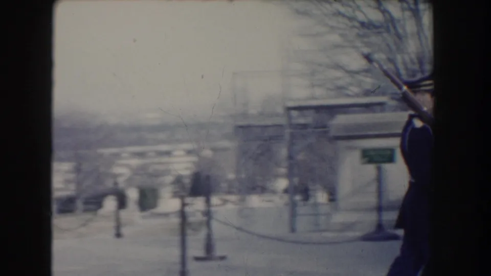 A uniformed soldier carrying a rifle with bayonet moves at the edge of the frame in Washington DC archival home-movie footage.