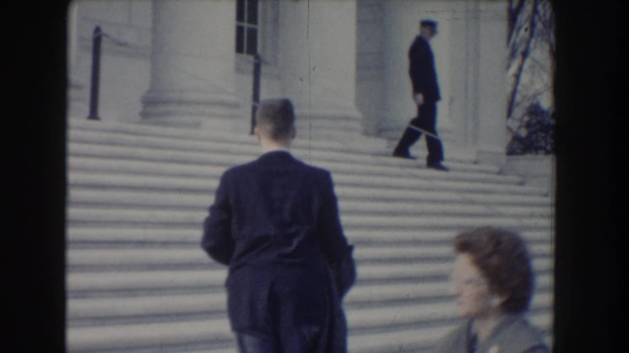 1960 Washington DC home-movie frame of suited pedestrians near the steps of a large stone civic building.