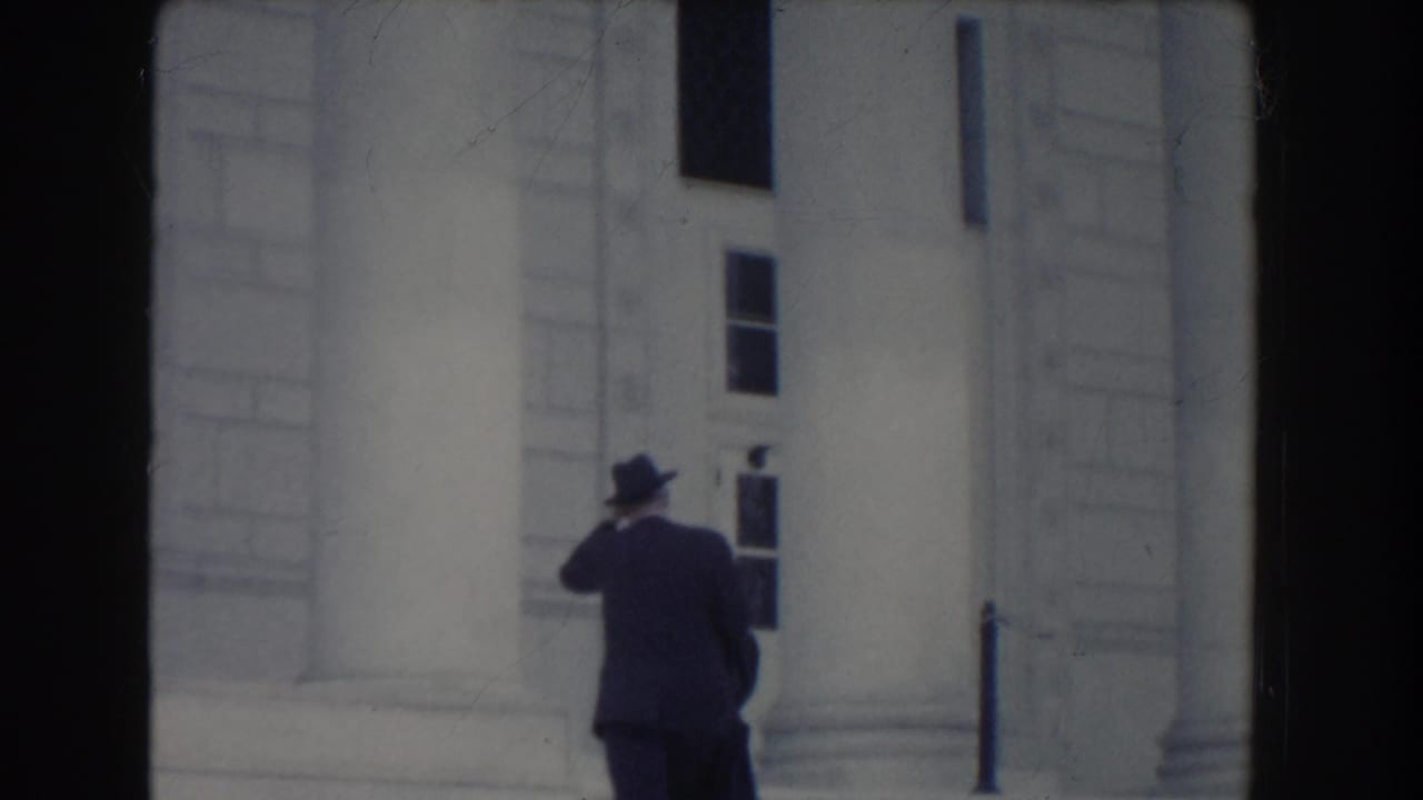 A suited man seen from behind moves along the steps of a white columned building in Washington DC, 1960.