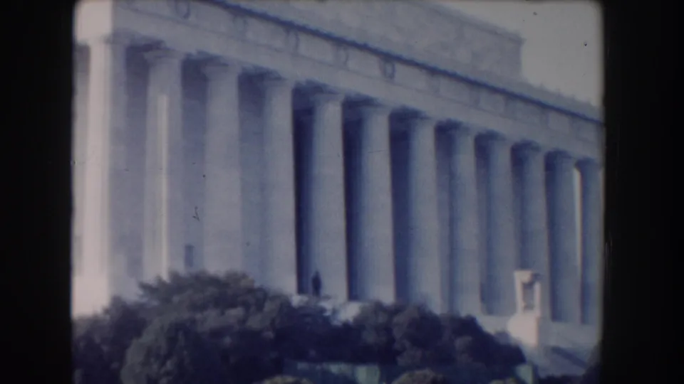 1960 Washington, DC home-movie frame showing the Lincoln Memorial facade and columns with trees below.