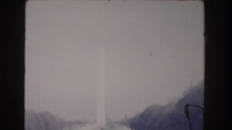 Late frame of the 1960 Washington, DC clip with the Washington Monument blurred in haze beyond road and trees.
