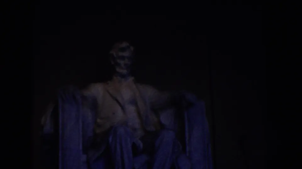 1960 8mm frame showing the Lincoln Memorial statue in Washington DC under dim blue-toned interior light.