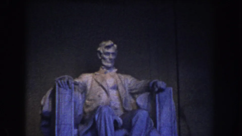 The statue of Abraham Lincoln remains centered in a dim 1960 home-movie view inside the Lincoln Memorial.