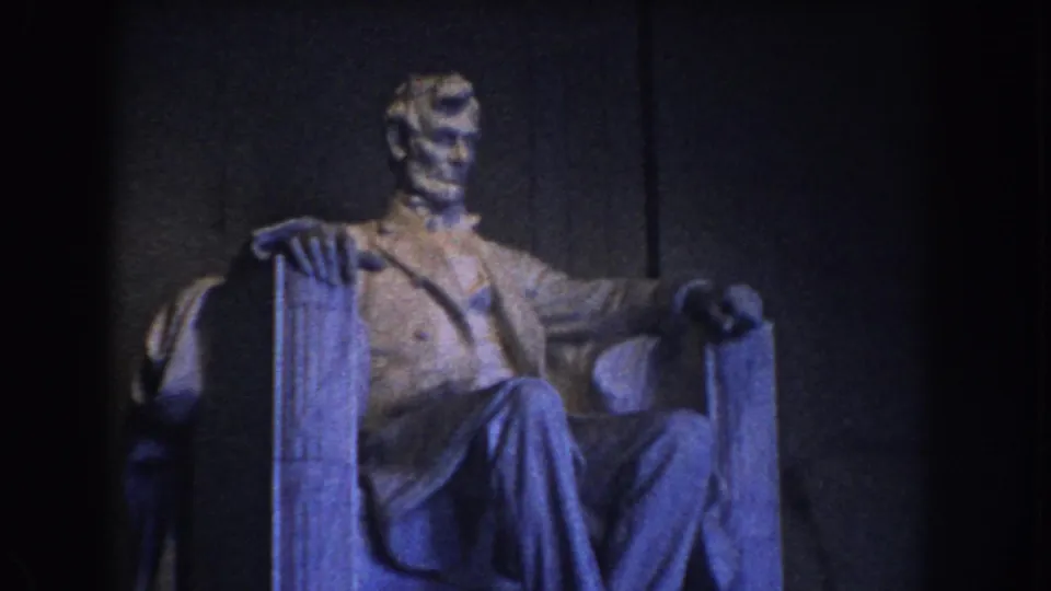 1960 Washington DC home-movie frame of the seated Lincoln statue in a dim interior with blue-purple color cast.