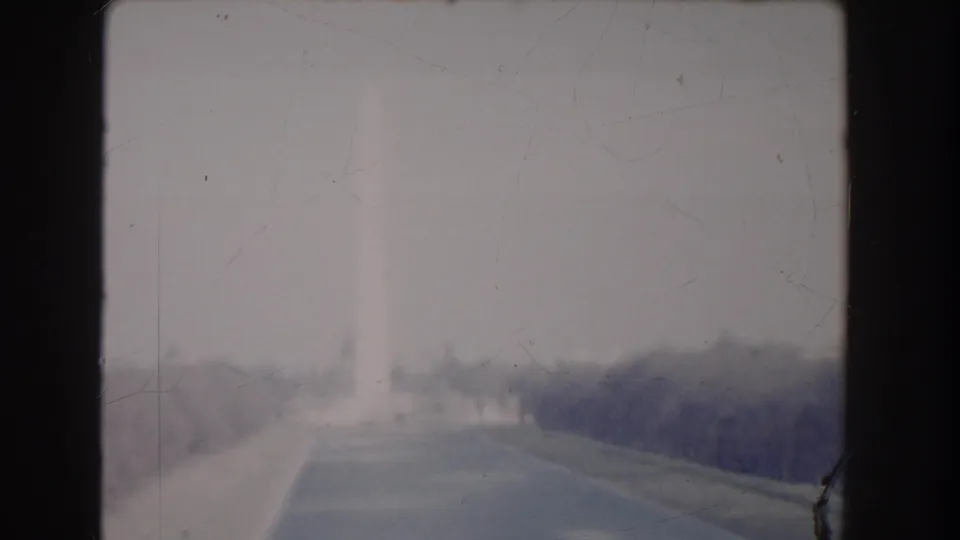 Soft 1960 8mm view in Washington, DC showing a hazy roadway leading toward a distant monument shape.