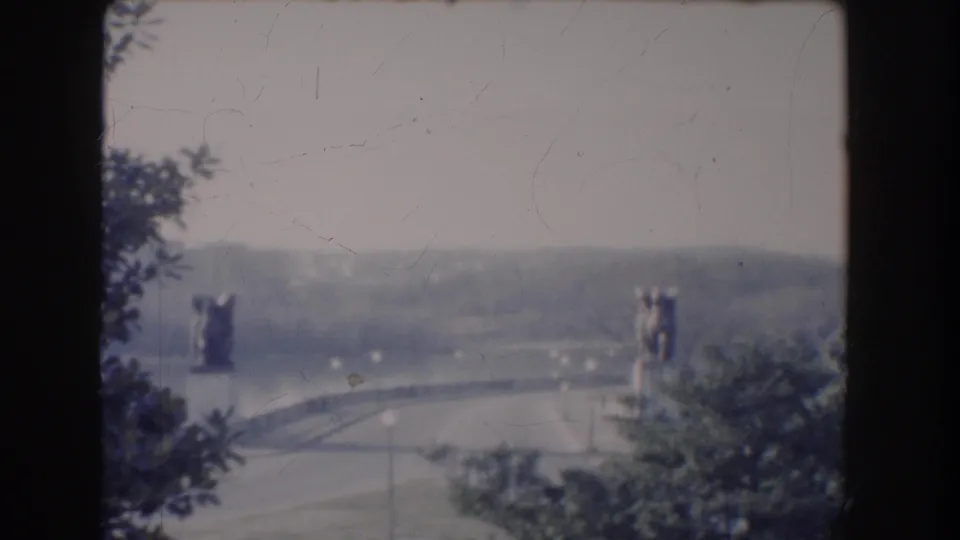 Faded-color 1960 Washington, DC view of a statue-flanked bridge and surrounding parkland under a pale sky.