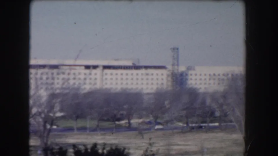 1960 Washington, DC home-movie view of a large distant institutional building beyond bare trees and open Mall grounds.
