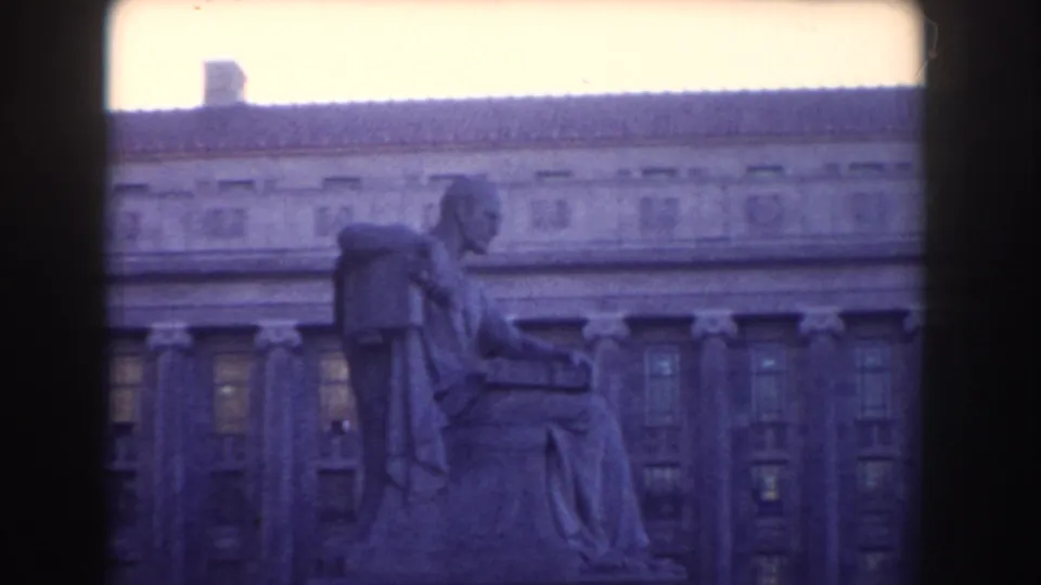 1960 Washington DC home-movie frame showing a side view of a seated public statue against a large institutional facade.