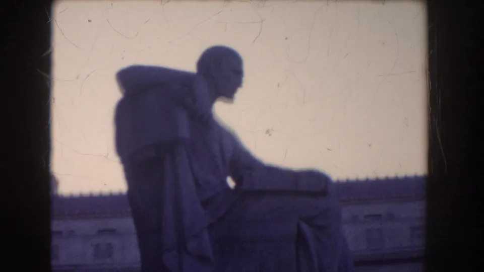 1960 Washington DC 8mm frame showing the seated statue in darker profile with sky and building roofline behind it.