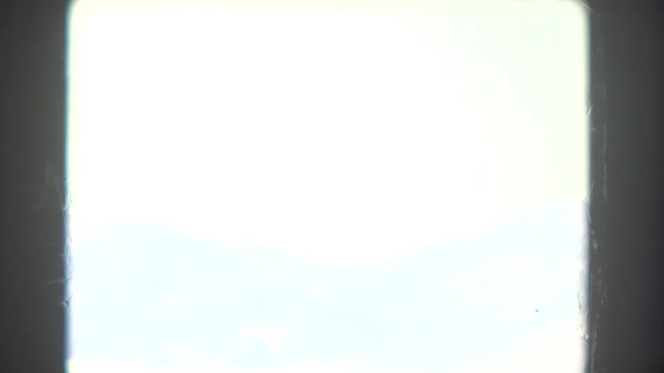 Very bright 8mm frame with dark gate edges and minimal readable detail, likely at the start of a travel landscape shot.