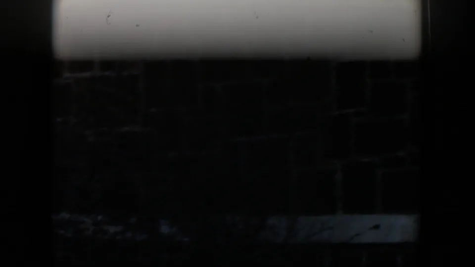 A dark, partially obscured 8mm frame shows structural edges and shadowed ground during the same porch sequence.