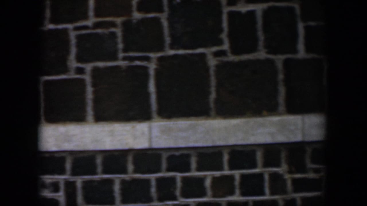 Dark stone wall with pale horizontal trim and heavy shadow.
