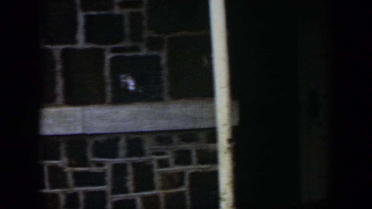 Stone wall, pale trim, white pole, and dark doorway at right.