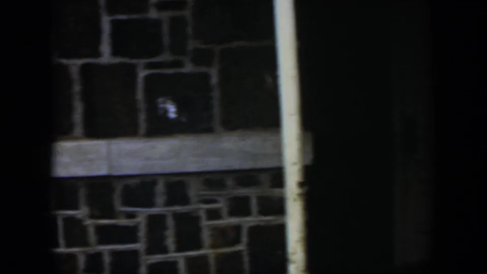 1951 Cuba 8mm frame with irregular masonry, a pale trim band, a weathered white pole, and a dark doorway or opening.