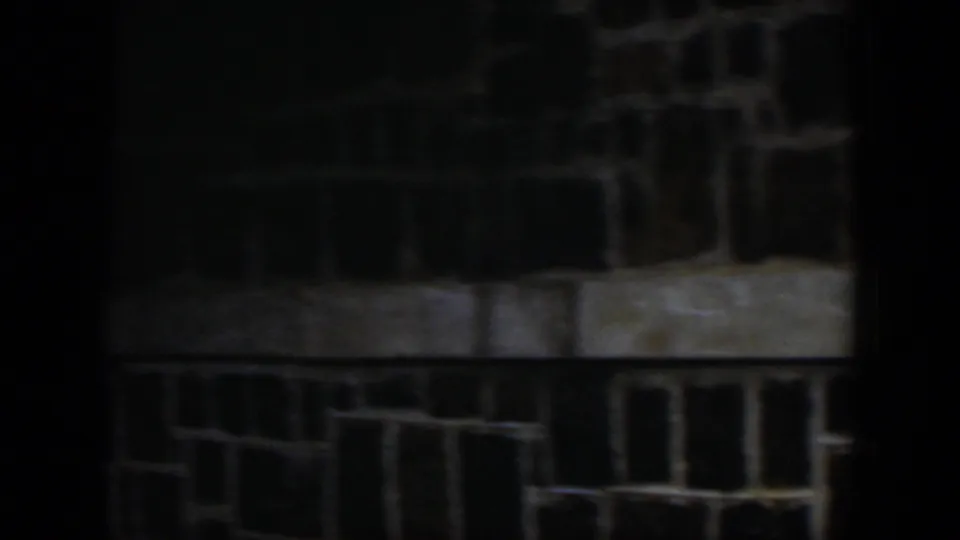 1951 Cuba 8mm frame of a dark masonry exterior with pale trim, deep shadow, and a partial opening at the edge.