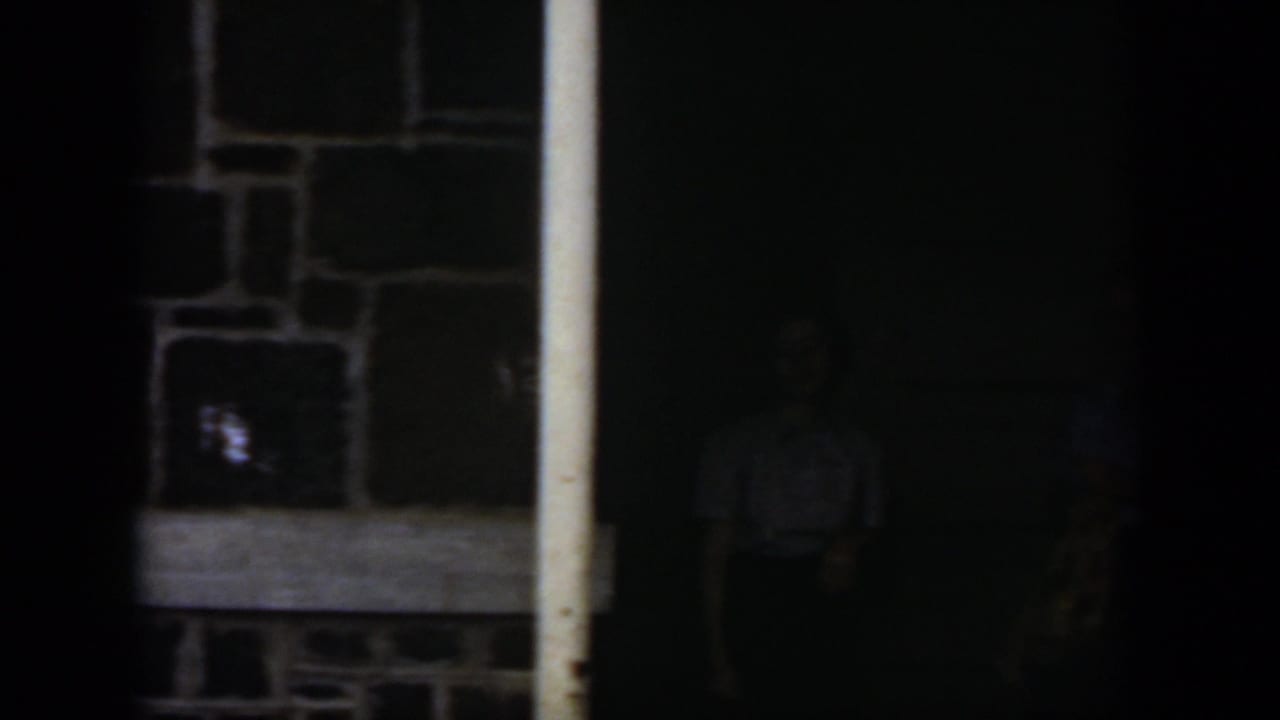 Dark frame with a stone wall and pale vertical doorway posts visible at the left.