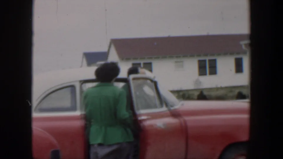 The woman turns toward the open red car door as the man stands partly obscured, ending the Cuba 1951 departure moment.