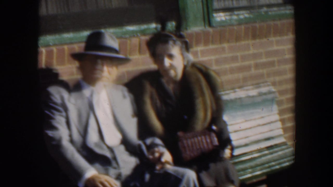 In 1951 Cuba home-movie footage, an elderly man in a light suit and fedora sits beside a woman in a dark fur-collared coat.