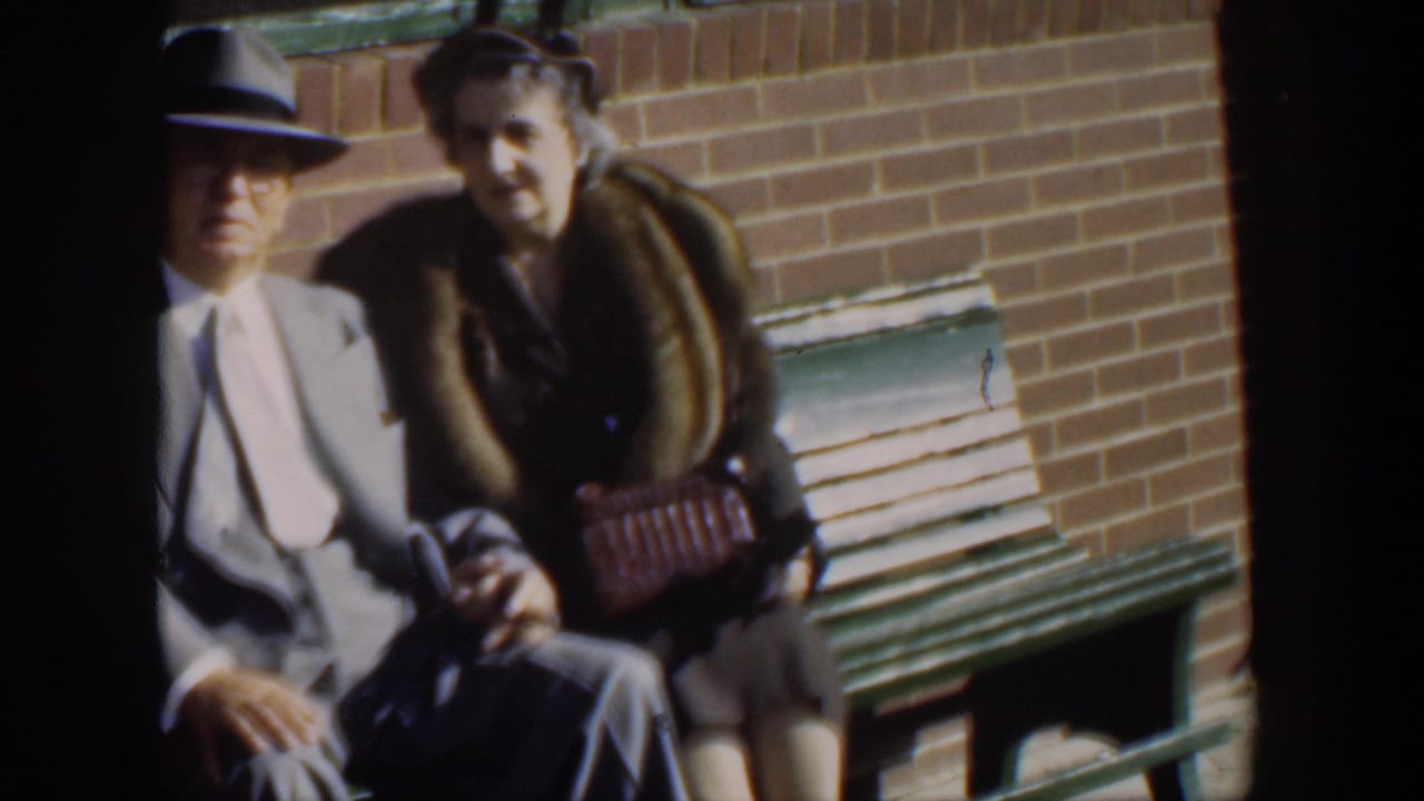 Older man and woman seated close together on a bench outdoors.