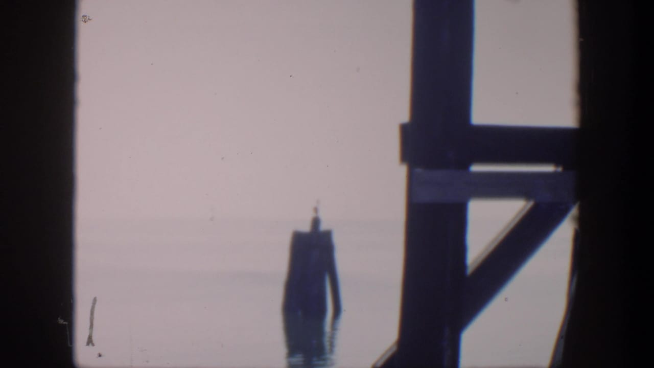 Pier supports and a distant buoy-like marker over calm water.