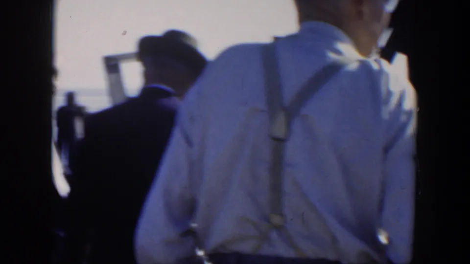 1951 Cuba waterfront scene with men in suits, hats, and suspenders standing close to the camera near marina railings and water.