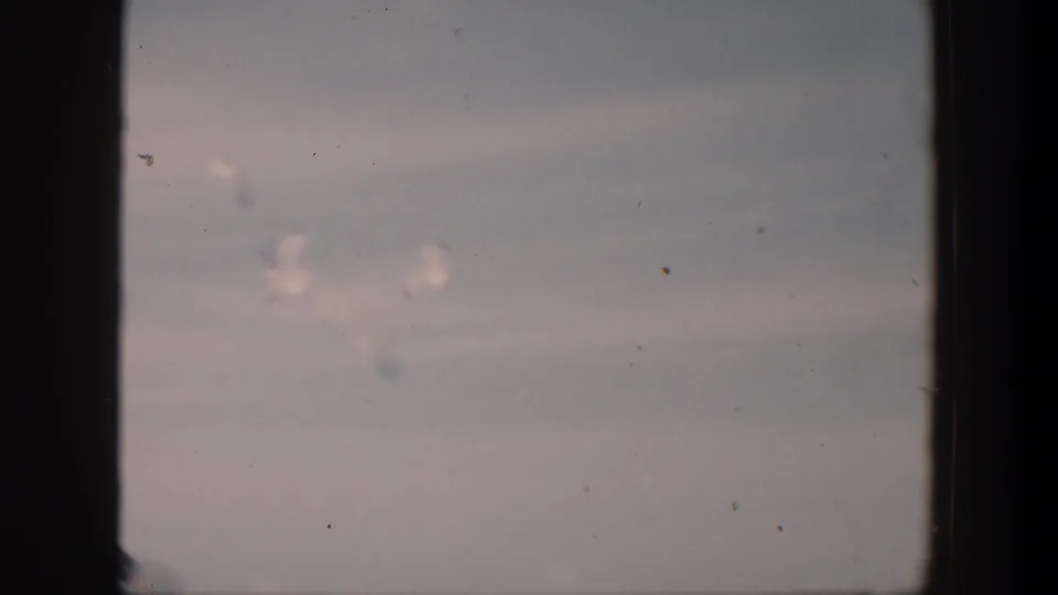 1951 Cuba 8mm frame with seagulls in a pale sky above the sea, viewed through dark film-frame edges.