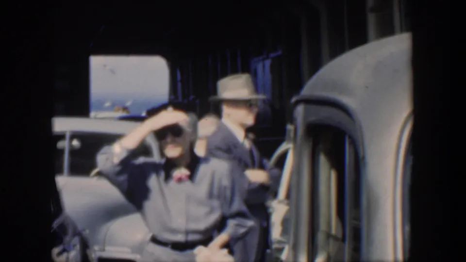 1951 Cuba frame showing a woman shading her eyes near a classic car, with men in hats in the background.