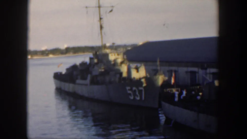 1951 Cuba home-movie view of destroyer 537 moored in harbor, partly obscured by a nearby vessel or pier edge, with water and shoreline beyond.