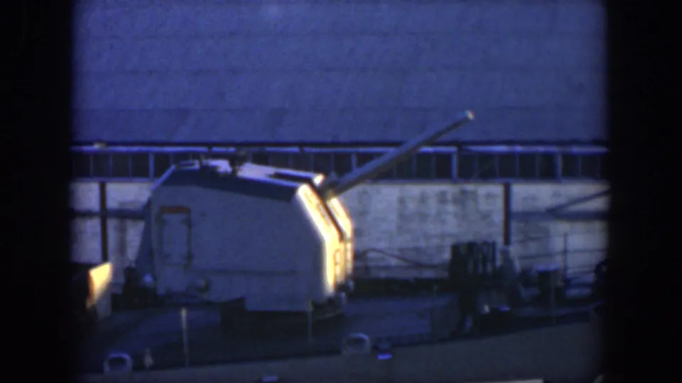 1951 Cuba 8mm frame showing the turret closer in view, with railings, cables, and industrial windows across the background.