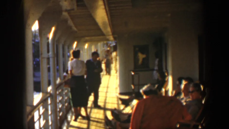 1951 Cuba home-movie frame showing passengers on a covered ship deck, with seated travelers, railings, and a sunlit walkway.