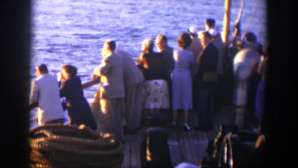 Passengers on a ship deck in Cuba 1951 gather at the railing and look across calm blue water in bright sunlight.