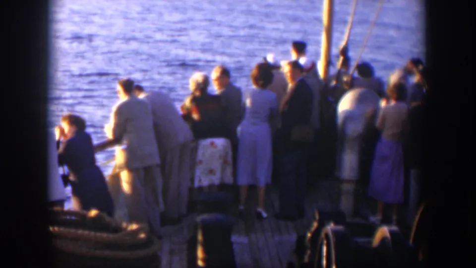 1951 Cuba home-movie frame of formally dressed passengers gathered on a boat deck beside calm blue water.